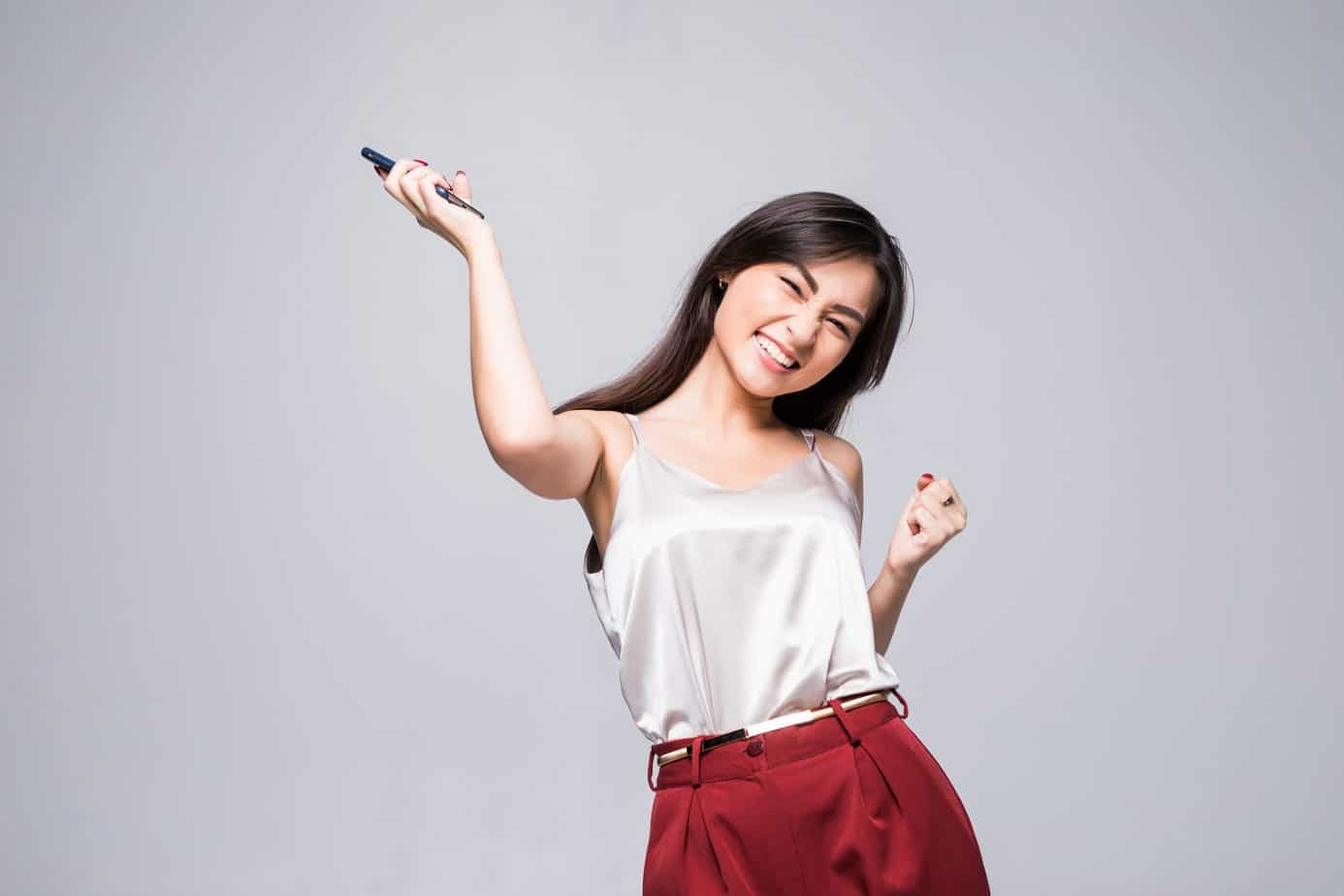 winning success asian woman happy ecstatic celebrating being winner isolated white wall waist up scaled